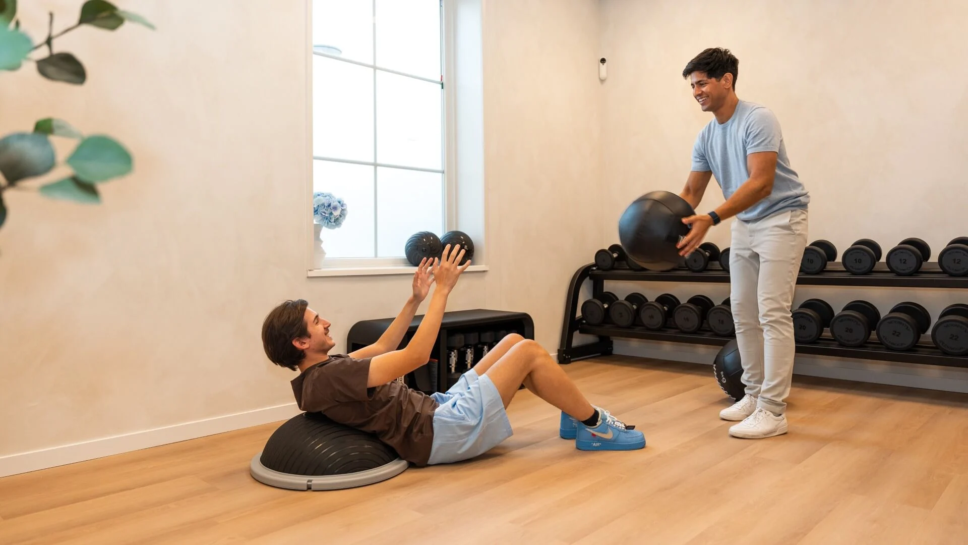 Fysiotherapeut begeleidt cliënt bij core-training met bal in de oefenruimte van Feel Fit Lochem