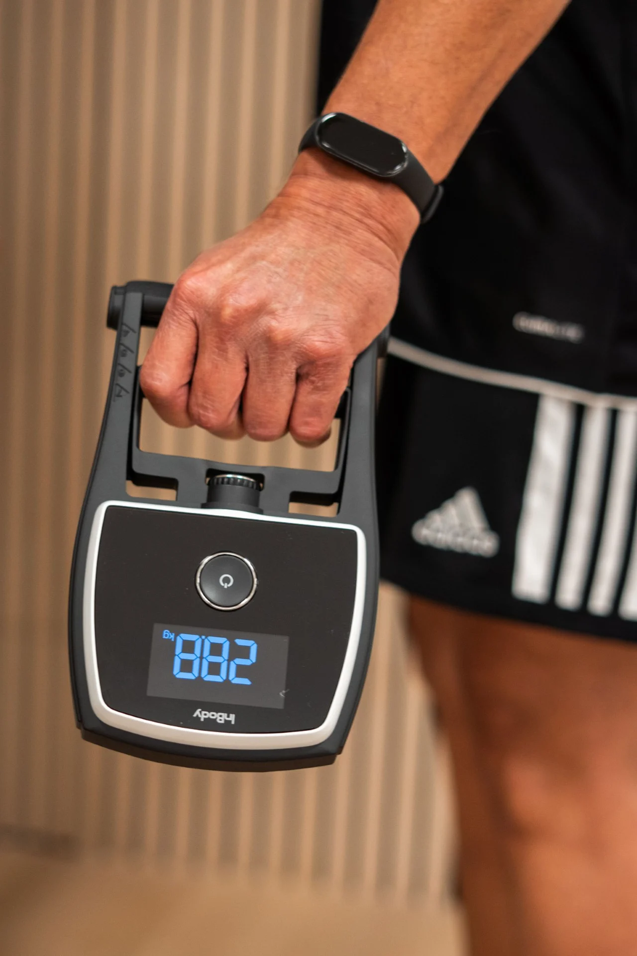 Hand houdt digitale handknijpkrachtmeter met display tijdens krachtmeting bij Feel Fit Lochem.