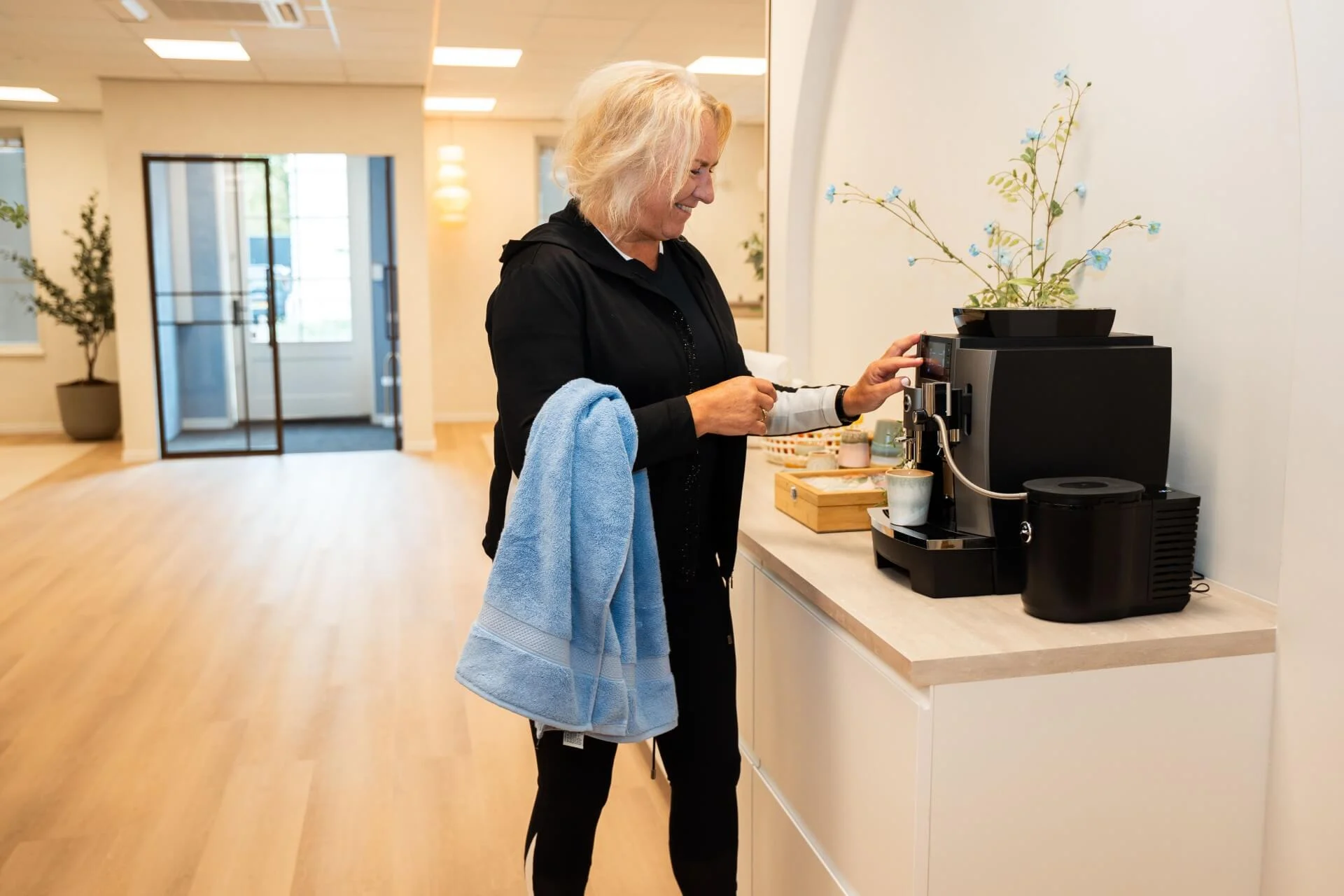 Cliënt geniet van een kop koffie in de lounge na fysiotherapie bij Feel Fit Lochem.