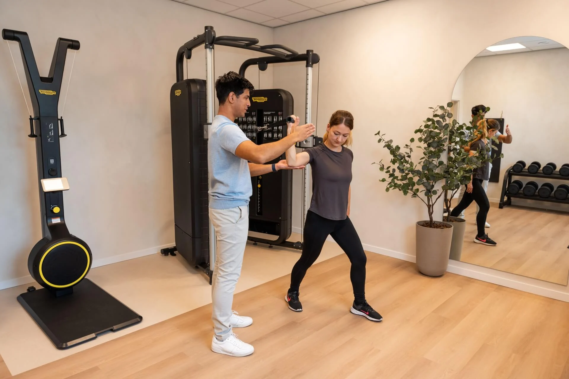 Manueel therapeut begeleidt cliënt bij mobiliteitsoefening in de praktijkruimte van Feel Fit Lochem.